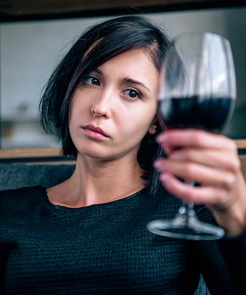 грустная женщина с бокалом вина в руке
