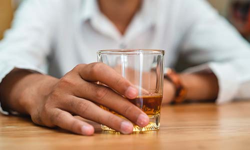 мужчина сидит за столом и держит в руке стакан с алкоголем